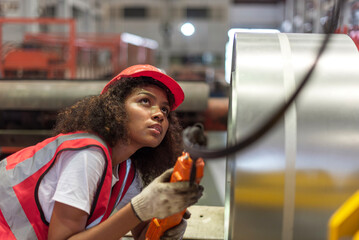 African female worker working with remote control's operating crane or lifting beam in factory