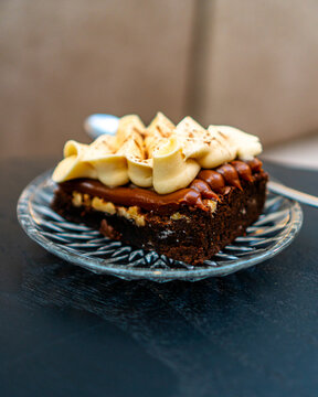 Delicate and gourmet chocolate cake portion with small metal spoon over black wooden table 