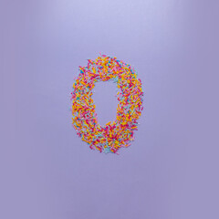 Number zero made of sugar sprinkles on a purple background. Creative alphabet concept.