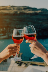 Women clink glasses of red wine against the backdrop of the sea. - 767149737