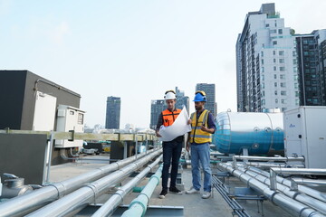Foreman engineer and contractor wearing reflective jacket, engineering helmet, holding blueprints...