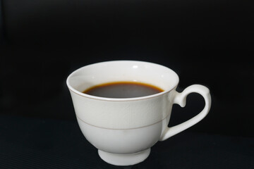 black coffee poured into a porcelain coffee cup on a black background