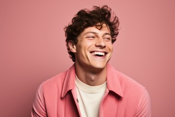 Fototapeta na wymiar Portrait of a happy young man laughing against a pink background.