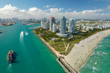 Obraz premium View from above of big container ship entering main channel in Miami harbor near South Beach high luxurious hotels and apartment buildings