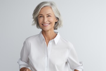 Portrait of smiling mature businesswoman standing with arms crossed against grey background