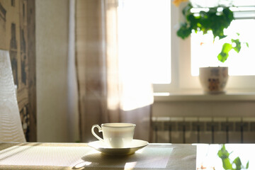 cup of hot steaming coffee on a sunny morning on the kitchen table