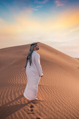 Fototapeta na wymiar Arab man stands alone in the desert and watching the sunset.