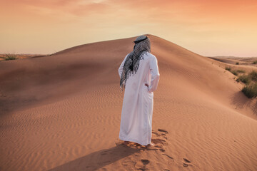 Arab man stands alone in the desert and watching the sunset.