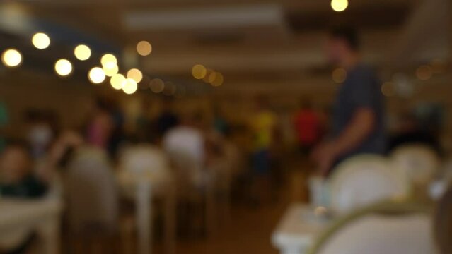 Blurred people choose food from buffet and eat in restaurant in hotel. Abstract defocused background of tourists in dining room.