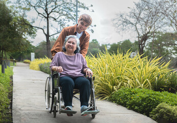 Asian family Elderly woman sitting in a wheelchair Smile and be happy with the man who takes care of you. Relationships and retirement concepts