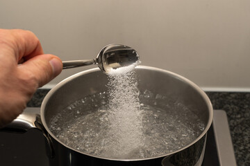 cooking water in a kitchen -bowl water with salt and spoon 