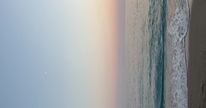 Vertical video. Pale sunset gradient over the sea.