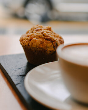 Latte and a chocolate muffin inside a city coffee shop and over a table with a yellow flower and beautiful interior design