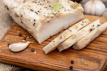 Fototapeta na wymiar Lard with garlic on wooden board. Sliced salted salo closeup