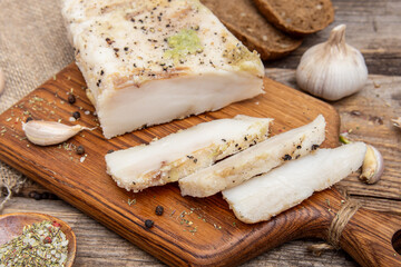 Lard with garlic on wooden board. Sliced salted salo