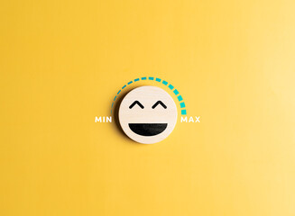 Happy smiling face on wooden circle with happiness gauge on yellow background. Mental health...
