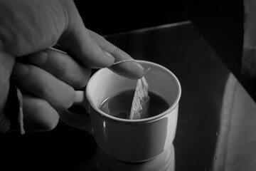 Putting tea bag into glass cup full of hot water 