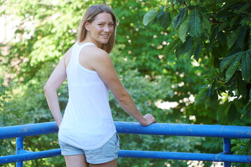 Happy smiling blonde young woman wears a white tank top with copy space or text space for print or design	
