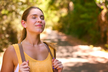 Young Woman Wearing Backpack Closing Eyes Enjoying Peace Of Hike Along Trail Through Countryside
