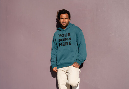 Mockup of man wearing customized hoodie by pink wall