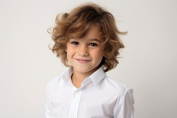 Portrait of a cute little boy with curly hair on gray background