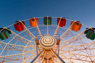 Enchanting Evening View of a Colorful Ferris Wheel Illuminated Against Blue Sky - 767203711