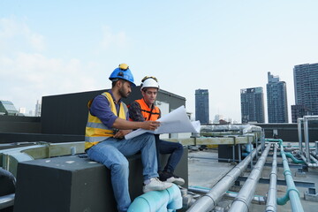 Foreman engineer and contractor engineer wearing reflective jacket, engineering helmet, holding...