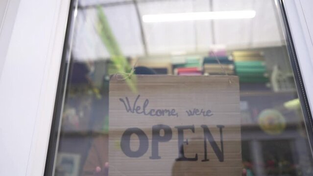 A female store manager changes the Closed to Open sign on the window