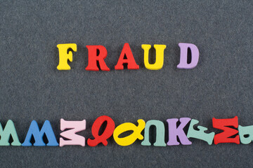 FRAUD word on black board background composed from colorful abc alphabet block wooden letters, copy space for ad text. Learning english concept.