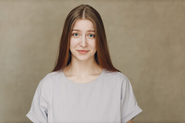 Portrait of young pretty smiling woman looking at camera against beige background - 767208596