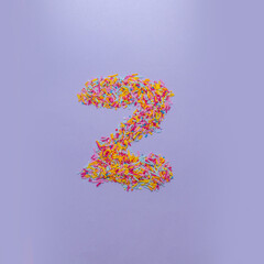 Letter Z made of sugar sprinkles. Creative alphabet concept on a purple background.