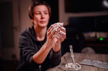 Close-up of hands coated in pottery clay, focused on shaping and creating, embodying the tactile...