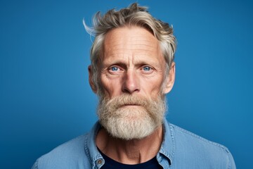 Portrait of a senior man with grey beard and mustache on blue background