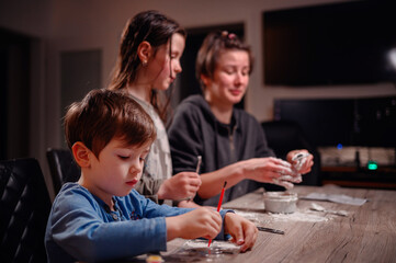 A focused family immerses in creativity, with children shaping clay and a young boy coloring,...