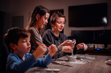 A focused family immerses in creativity, with children shaping clay and a young boy coloring, capturing a moment of artistic expression and familial bonding