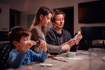A focused family immerses in creativity, with children shaping clay and a young boy coloring, capturing a moment of artistic expression and familial bonding