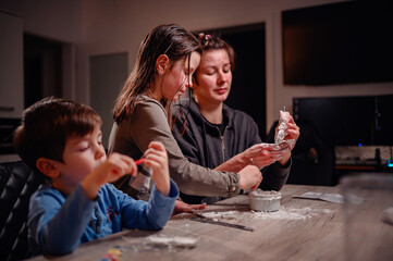 A focused family immerses in creativity, with children shaping clay and a young boy coloring,...
