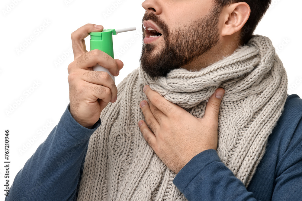 Canvas Prints Young man with scarf using throat spray on white background, closeup