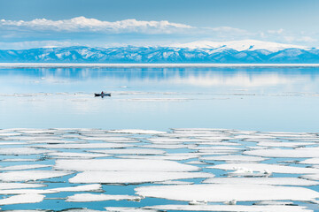 Melting ice on Baikal lake. Kayak sailing between ice floes on the lake.