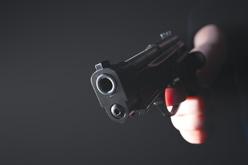 Tense Moment: Close-Up of a Hand Gripping a Loaded Pistol in Darkness