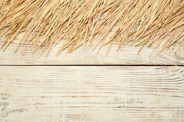 Heap of dried hay on white wooden background, flat lay. Space for text