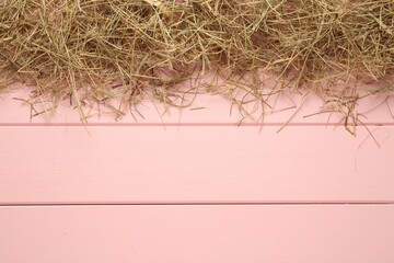 Heap of dried hay on pink wooden background, flat lay. Space for text