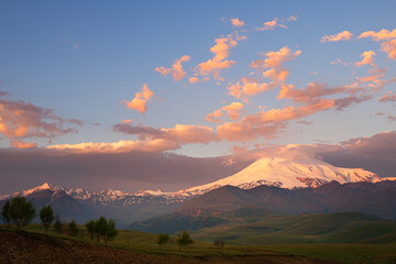 Elbrus mount with pink clouds at sunrise. View from Gil-Su valley in North Caucasus, Russia