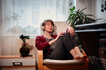With closed eyes and headphones on, a woman is immersed in a private concert, feeling every beat in...
