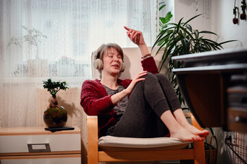 With closed eyes and headphones on, a woman is immersed in a private concert, feeling every beat in...