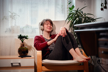 With closed eyes and headphones on, a woman is immersed in a private concert, feeling every beat in...