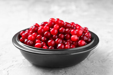 Fresh ripe cranberries in bowl on grey table, closeup