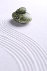 Zen garden stones on white sand with pattern. Space for text