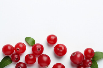 Fresh ripe cranberries and green leaves on white background, flat lay. Space for text