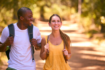 Close Up Of Young Active Couple Wearing Backpacks Hiking Along Trail Through Countryside